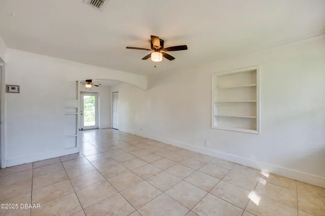 an empty room with windows and fan