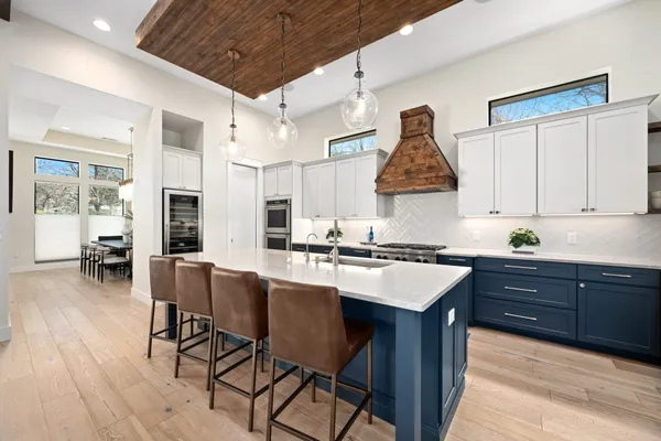 a kitchen with stainless steel appliances a stove a sink dishwasher and a dining table with wooden floor