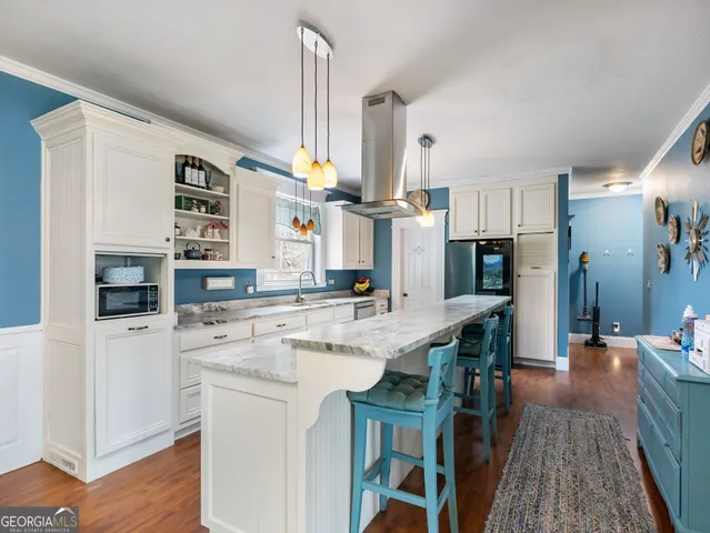 a kitchen with a wooden floor and a view of living room