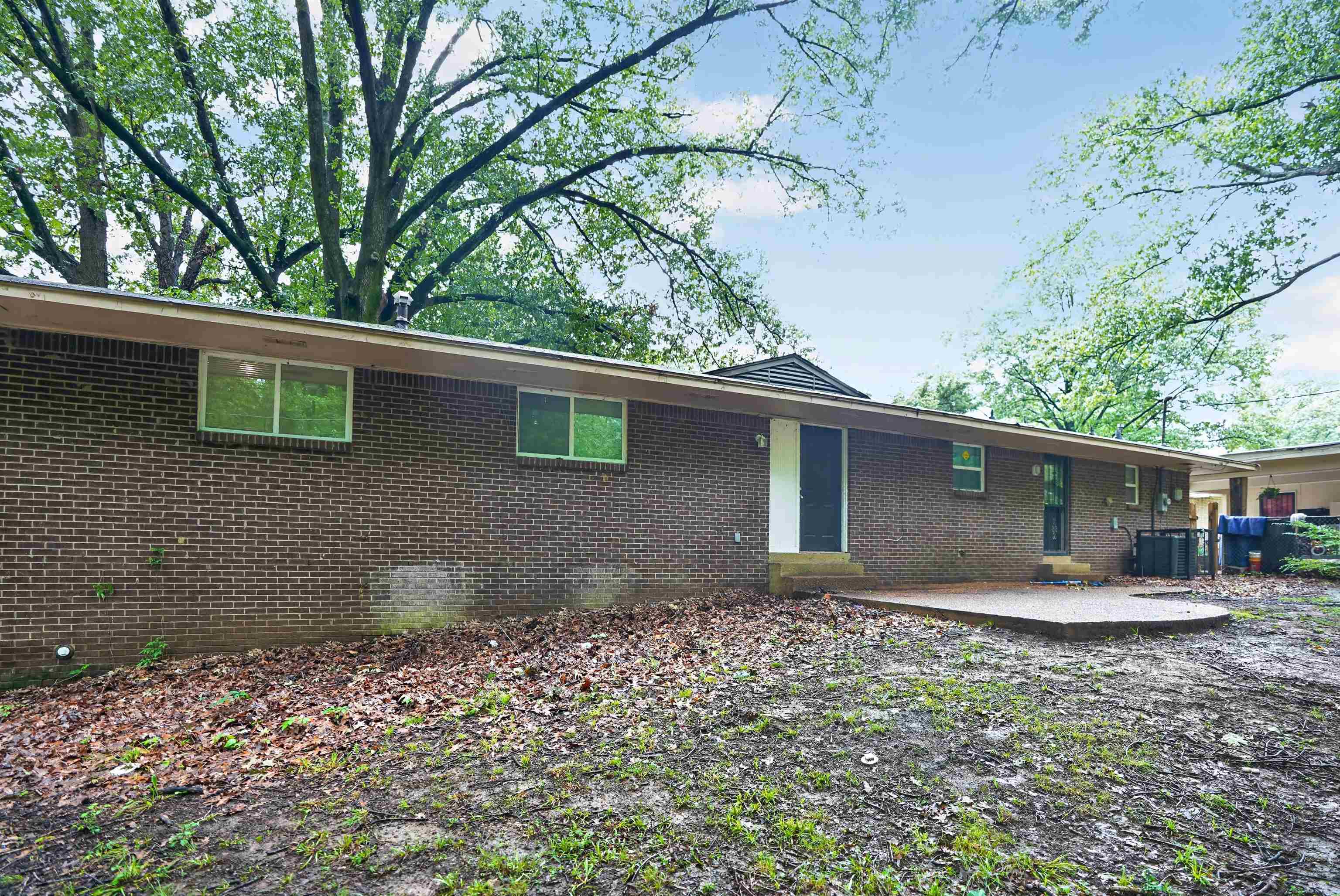 1890 Pennel Road Memphis, TN 38116 - Photo 3 of 25 Brick exterior featuring a flat roofline, multiple windows, a rear entry door, and a concrete patio