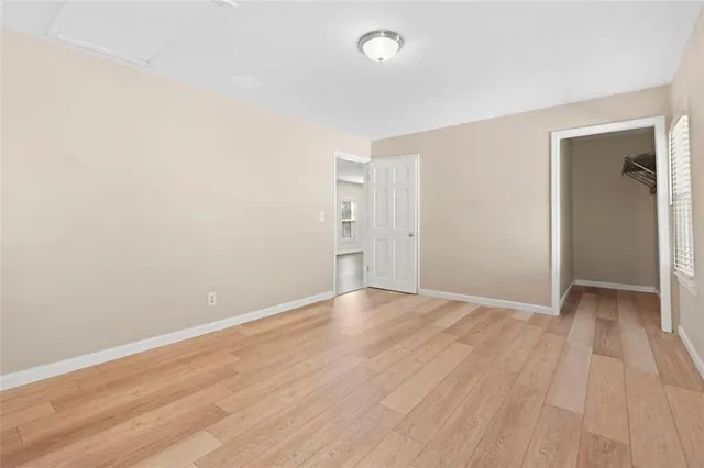a view of an empty room with wooden floor and closet