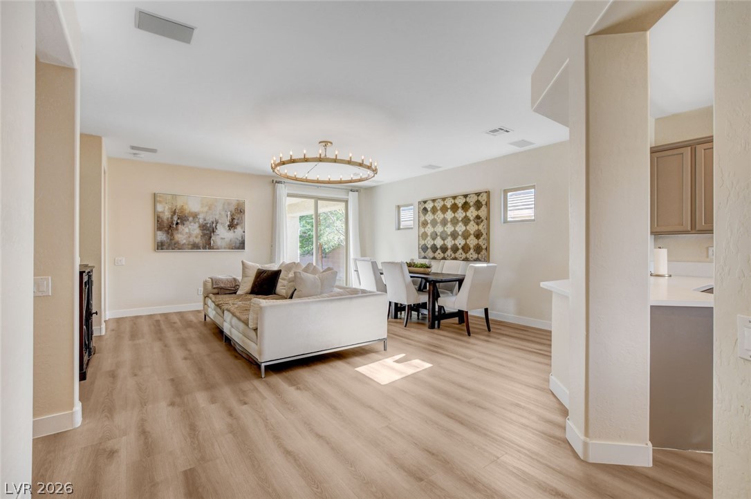 2649 Rue Marquette Avenue Henderson, NV 89044 - Photo 7 of 55 An inviting open-concept living and dining area with warm wood-tone flooring and elegant lighting.
