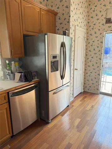 a utility room with stainless steel appliances wooden floor and a window