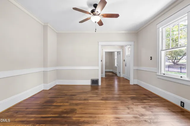 a view of an empty room with a window and wooden floor