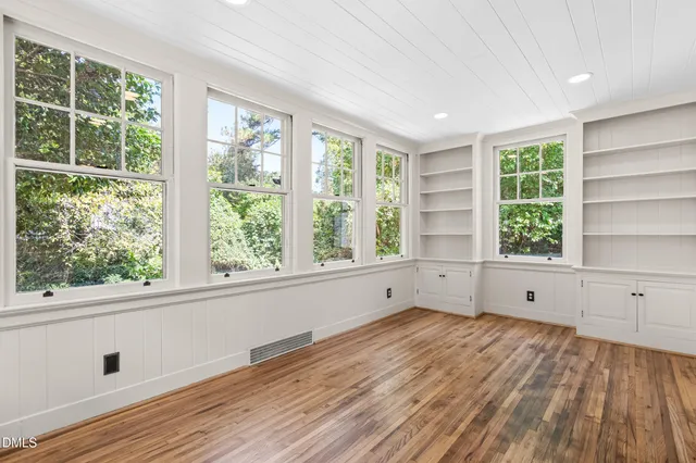 an empty room with wooden floor and windows