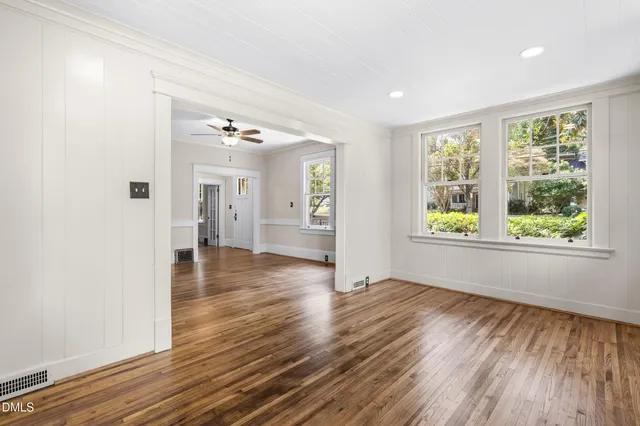 a view of empty room with wooden floor and fan