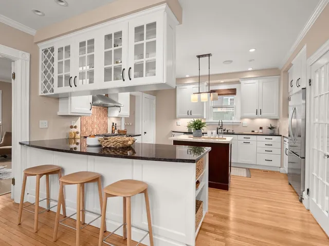 a kitchen with stainless steel appliances kitchen island granite countertop a table chairs sink and cabinets