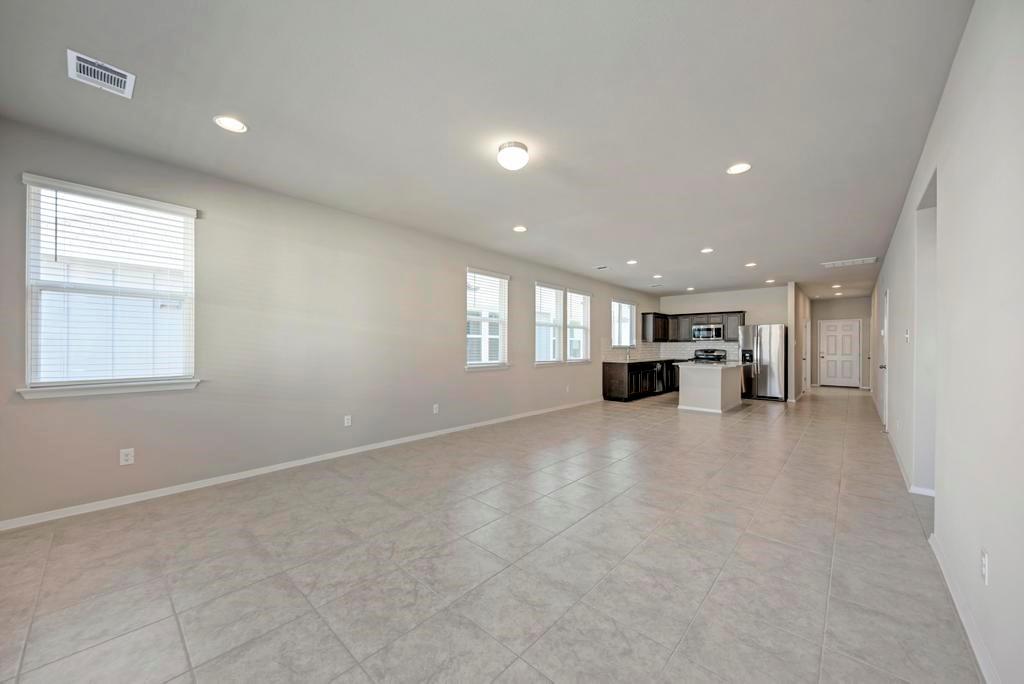 1209 Goforth Road Kyle, TX 78640 - Photo 14 of 32 An open-concept living area with abundant natural light flows seamlessly into a modern kitchen.