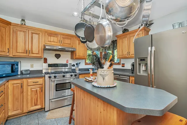 a kitchen with stainless steel appliances granite countertop a sink a stove and a wooden floors