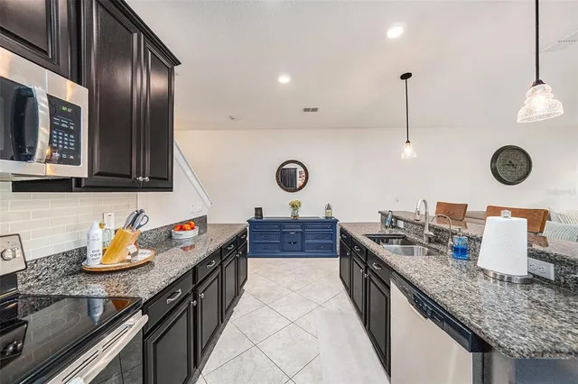a kitchen with stainless steel appliances granite countertop a sink a stove and a wooden floors
