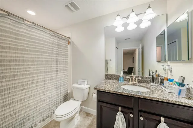 a bathroom with a granite countertop sink a toilet and a mirror
