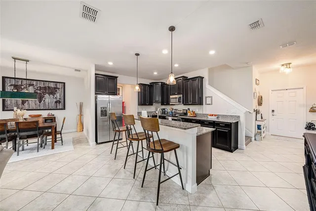 a kitchen with stainless steel appliances kitchen island granite countertop a table chairs and a stove