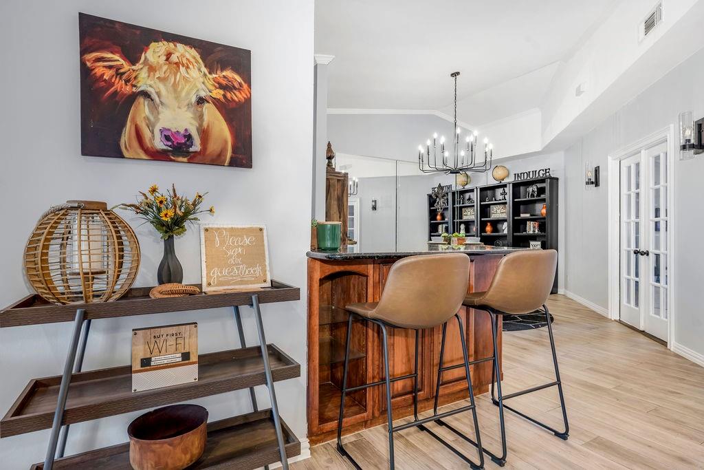 3330 Timberview Road Dallas, TX 75229 - Photo 17 of 39 Bar featuring lofted ceiling, french doors, hanging light fixtures, light hardwood / wood-style flooring, and a chandelier