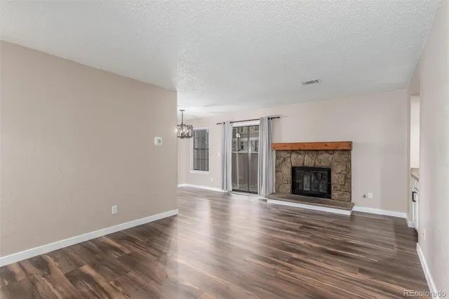 a view of an empty room with wooden floor fireplace and a window