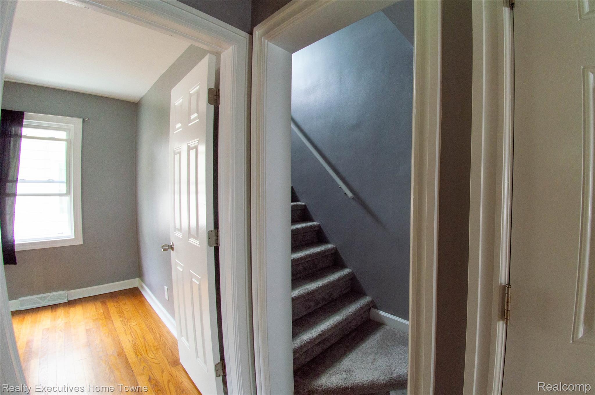 2676 Cumberland Road Berkley, MI 48072 - Photo 15 of 38 Interior hallway featuring a paneled door, doorway with white trim, and a carpeted staircase with a handrail