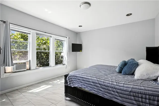 a bedroom with a large bed and a flat tv screen on dresser