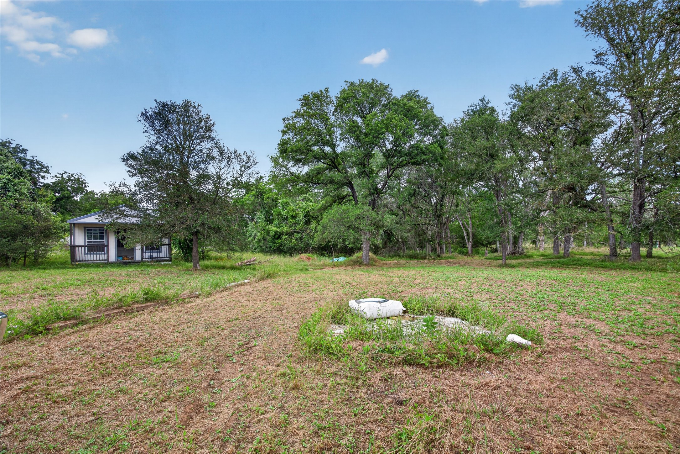 266 Beaver Road Elgin, TX 78621 - Photo 17 of 40 A tranquil cottage rests amidst a verdant landscape, offering a serene escape.