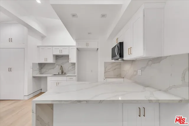 a kitchen with stainless steel appliances sinks a refrigerator and white cabinets