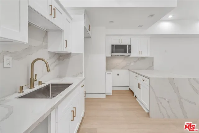 a view of a kitchen with white cabinets and a sink