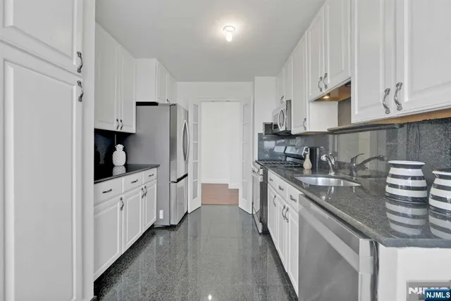 a kitchen with granite countertop white cabinets and stainless steel appliances