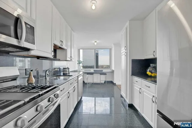 a kitchen with stainless steel appliances granite countertop a stove a sink and a refrigerator