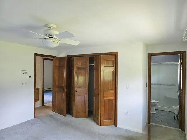 an empty room with closet and a ceiling fan