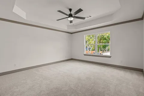 an empty room with ceiling fan and window