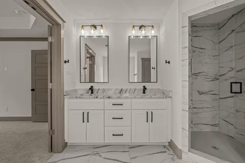 a bathroom with a double vanity sink mirror and shower