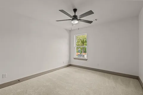 an empty room with window and ceiling fan