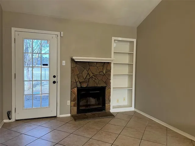 a view of an empty room with a fireplace and a window