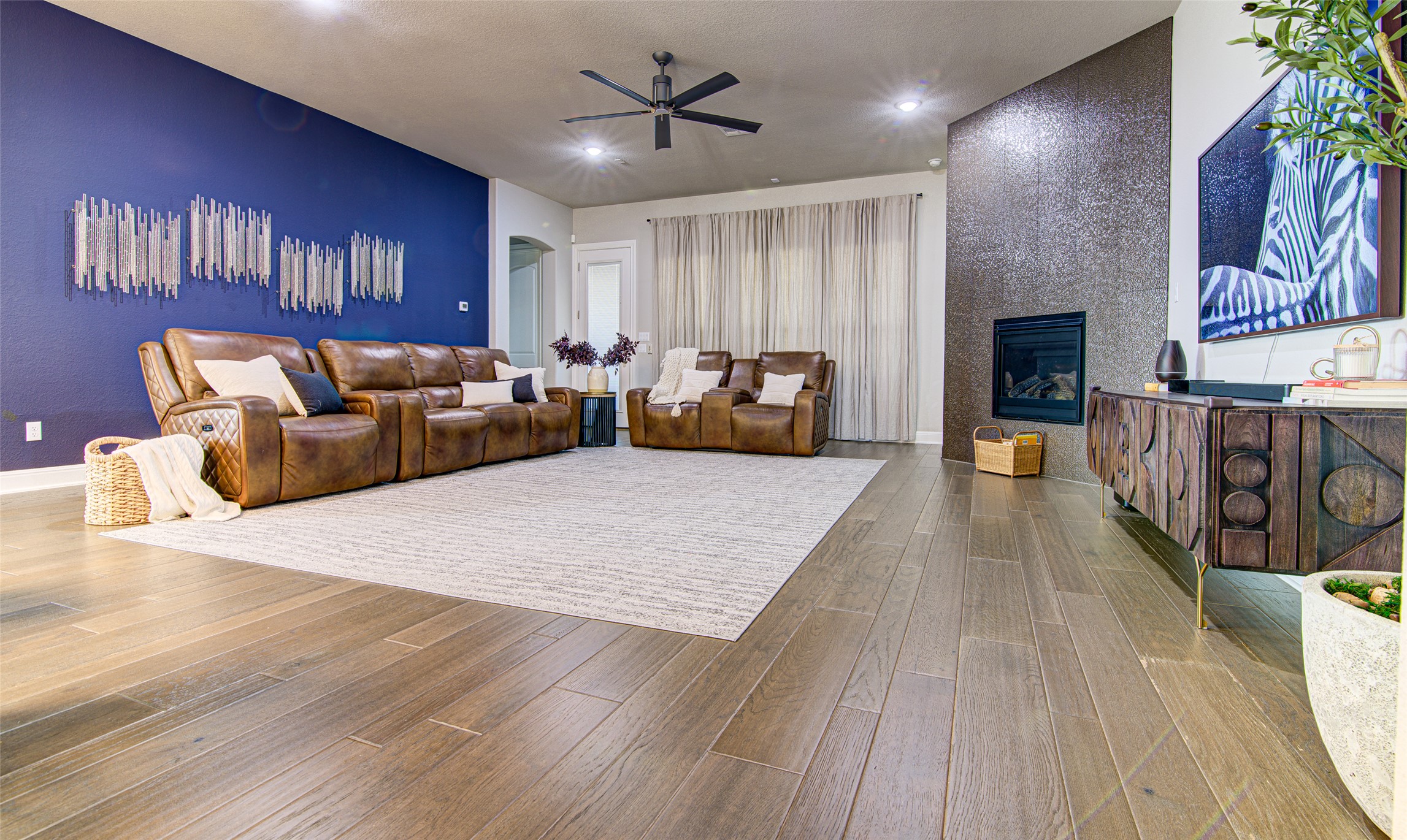4309 Olive Grv Cove Leander, TX 78641 - Photo 13 of 27 Living area featuring arched walkways, an accent wall, ceiling fan, and a tile fireplace