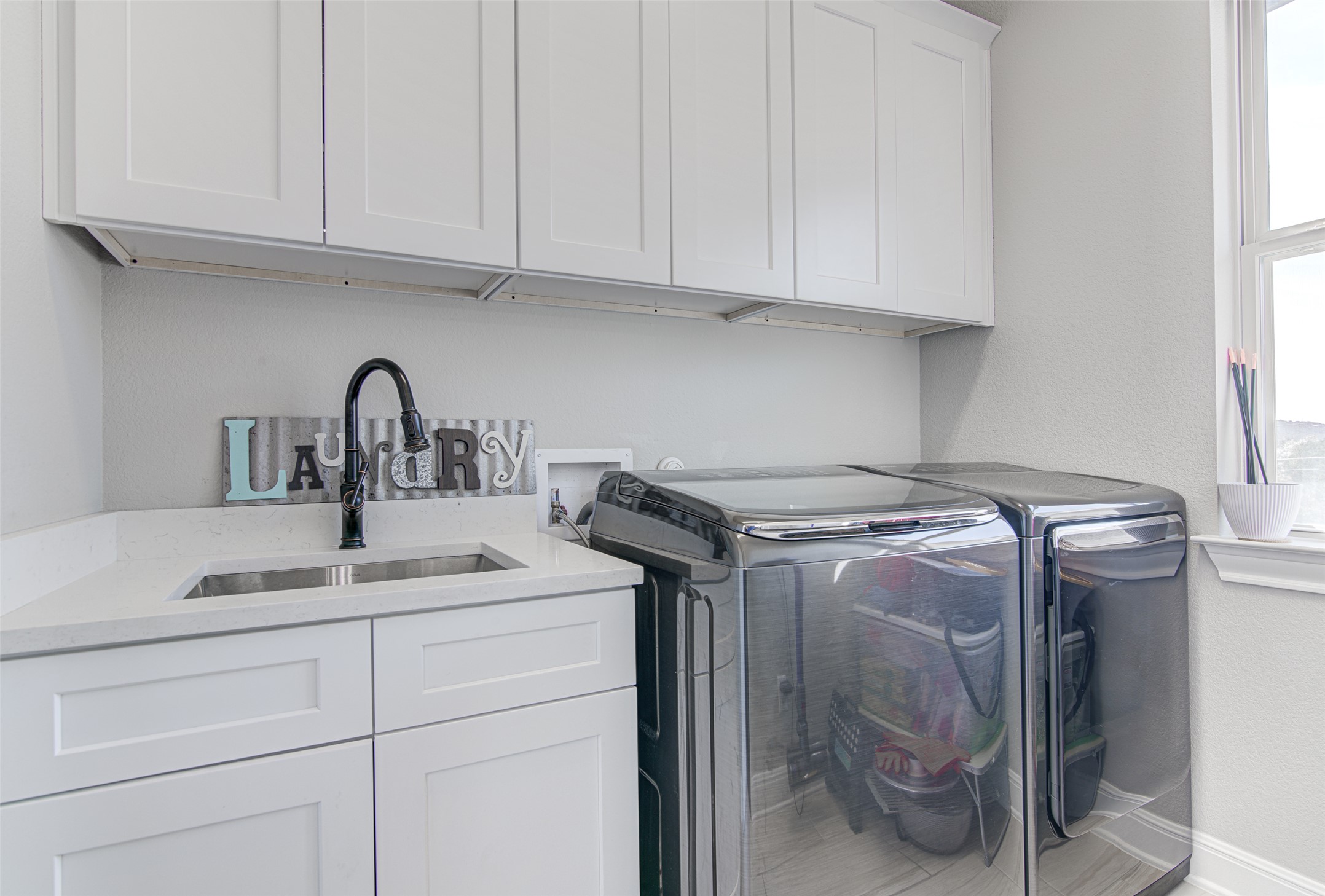 4309 Olive Grv Cove Leander, TX 78641 - Photo 14 of 27 Laundry room with cabinet space, washer and dryer, and a textured wall