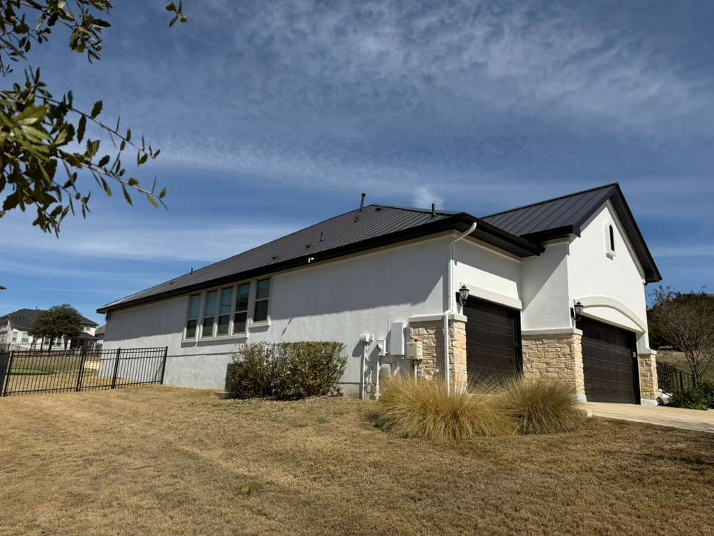 4309 Olive Grv Cove Leander, TX 78641 - Photo 26 of 27 View of property exterior with stucco siding, a garage, stone siding, driveway, and a metal roof
