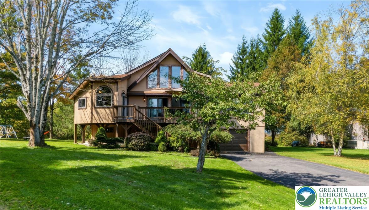 1605 Ridgeview Drive Lake Ariel, PA 18436 - Photo 2 of 40 Mature trees frame a multi-level wood siding home featuring a spacious elevated deck and paved driveway.