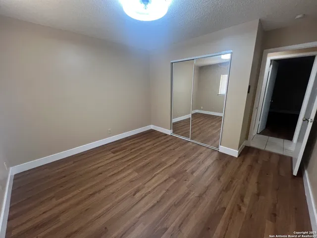 an empty room with wooden floor and mirror