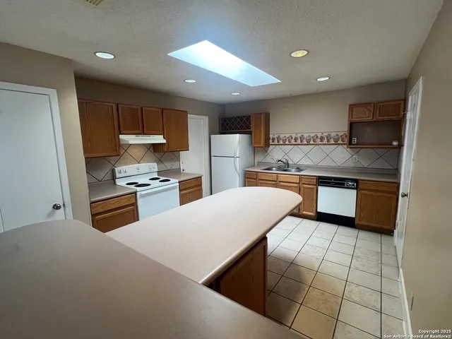 a kitchen with stainless steel appliances a sink a stove a refrigerator cabinets and a kitchen island