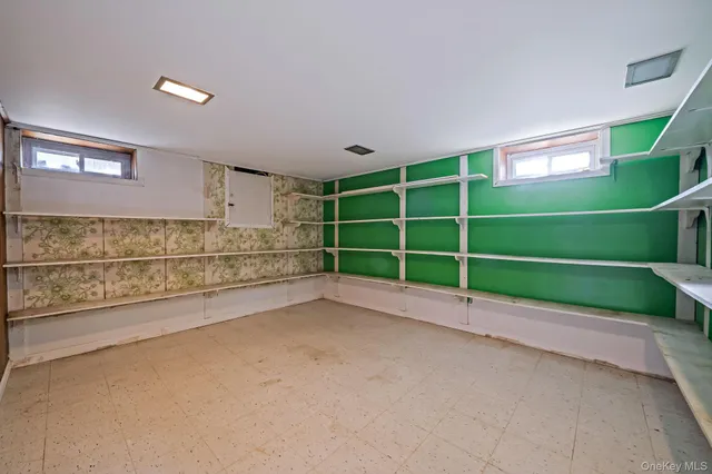a view of an empty room with a window and a kitchen view