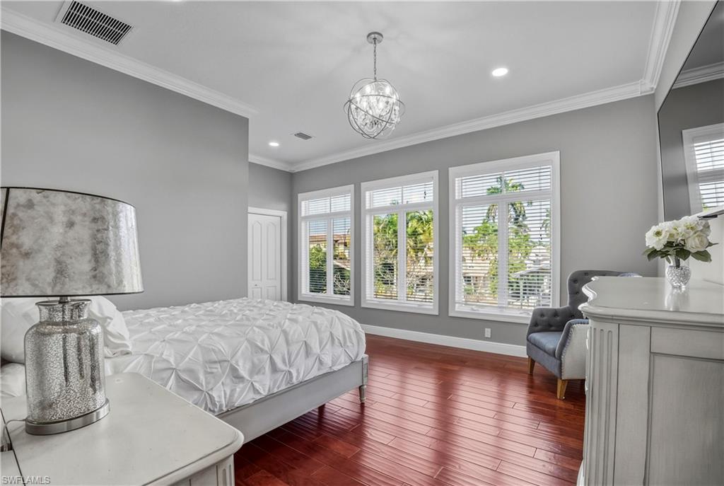 453 18th Avenue South Naples, FL 34102 - Photo 30 of 47 a spacious bedroom with a large bed and a chandelier