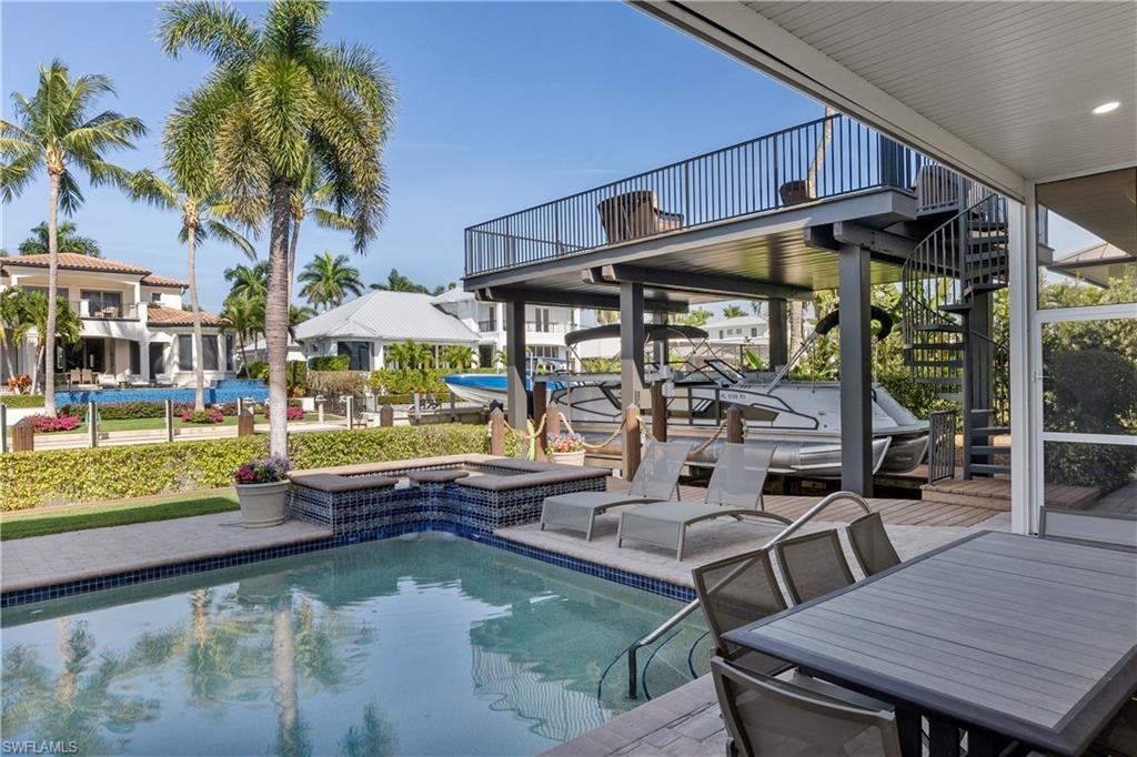 453 18th Avenue South Naples, FL 34102 - Photo 38 of 47 a view of a patio with table and chairs potted plants and palm tree