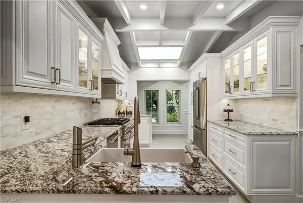 a kitchen with stainless steel appliances granite countertop a stove and white cabinets with wooden floor