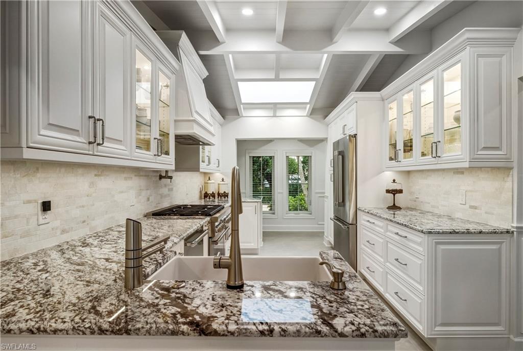 453 18th Avenue South Naples, FL 34102 - Photo 6 of 47 a kitchen with stainless steel appliances granite countertop a stove and white cabinets with wooden floor