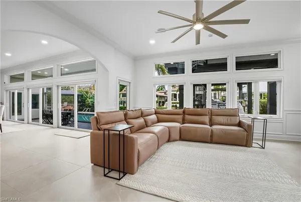 a living room with furniture large windows and a chandelier
