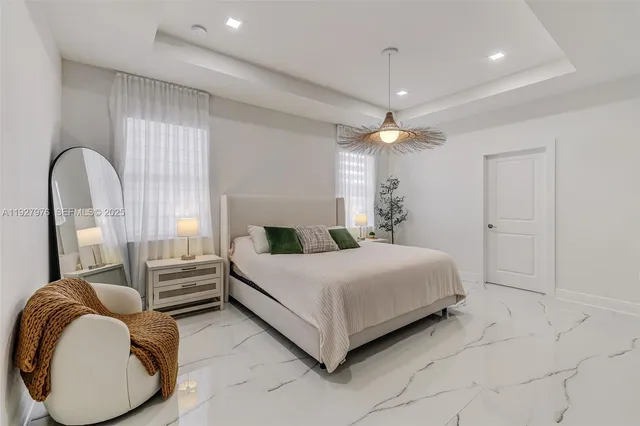 a spacious bedroom with a bed a chandelier and window