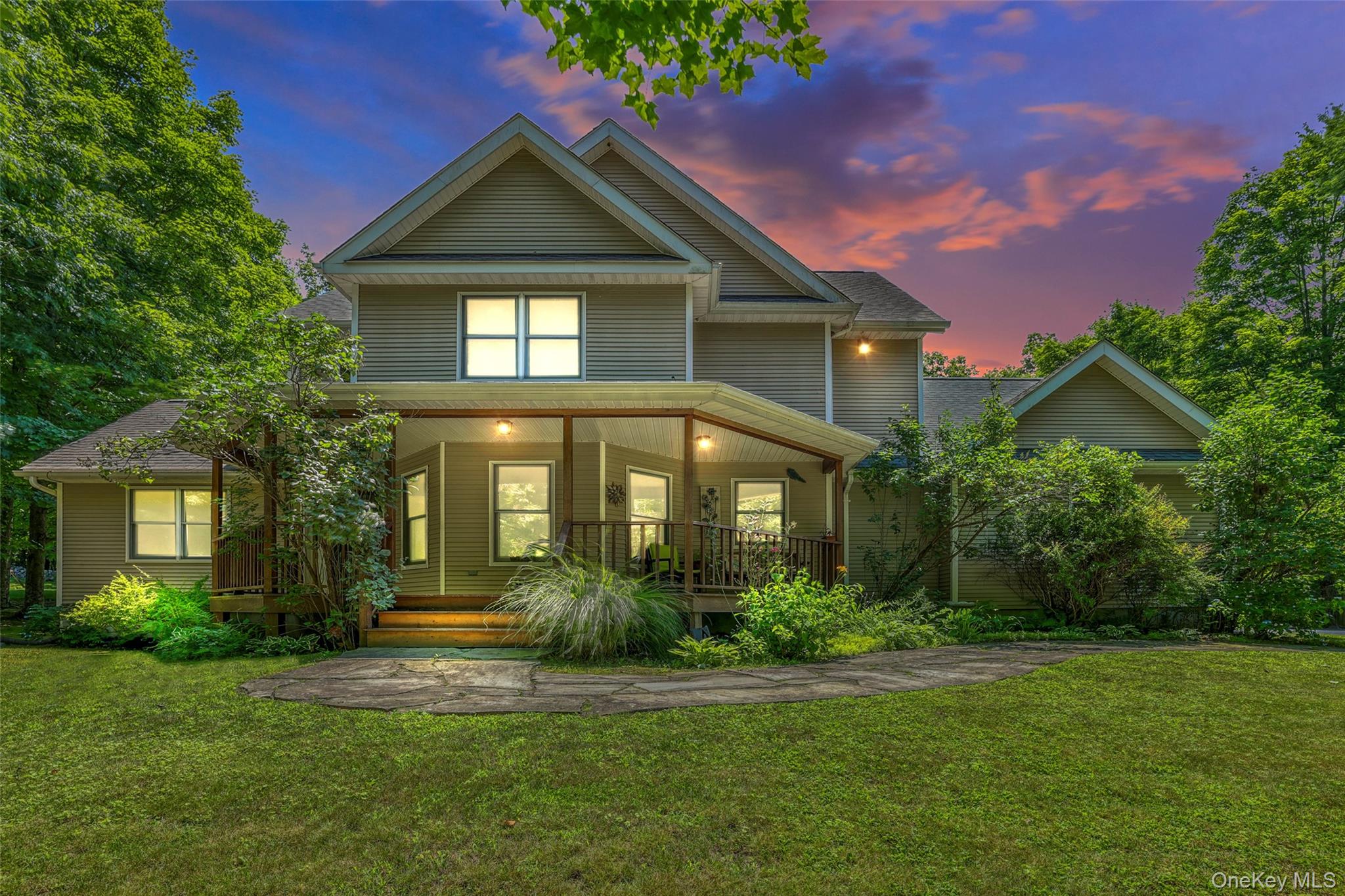 View of front of home featuring covered porch, a lawn, and a shingled roof
