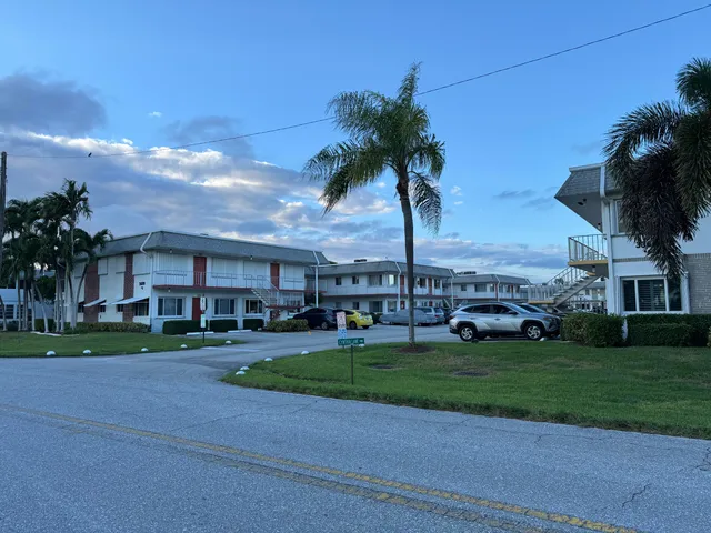 a view of a big house with a big yard and palm trees