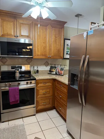 a kitchen with stainless steel appliances granite countertop a refrigerator a stove and a sink