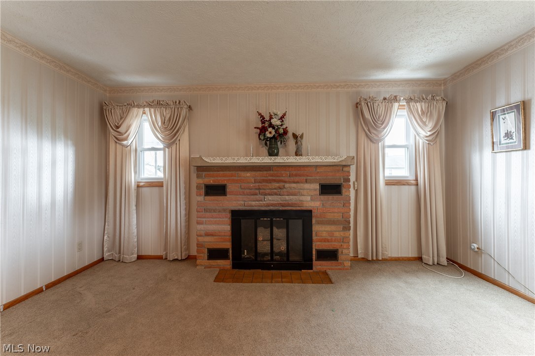 4833 Angling Road Wooster, OH 44691 - Photo 17 of 49 Unfurnished living room with a textured ceiling, ornamental molding, light colored carpet, and a fireplace