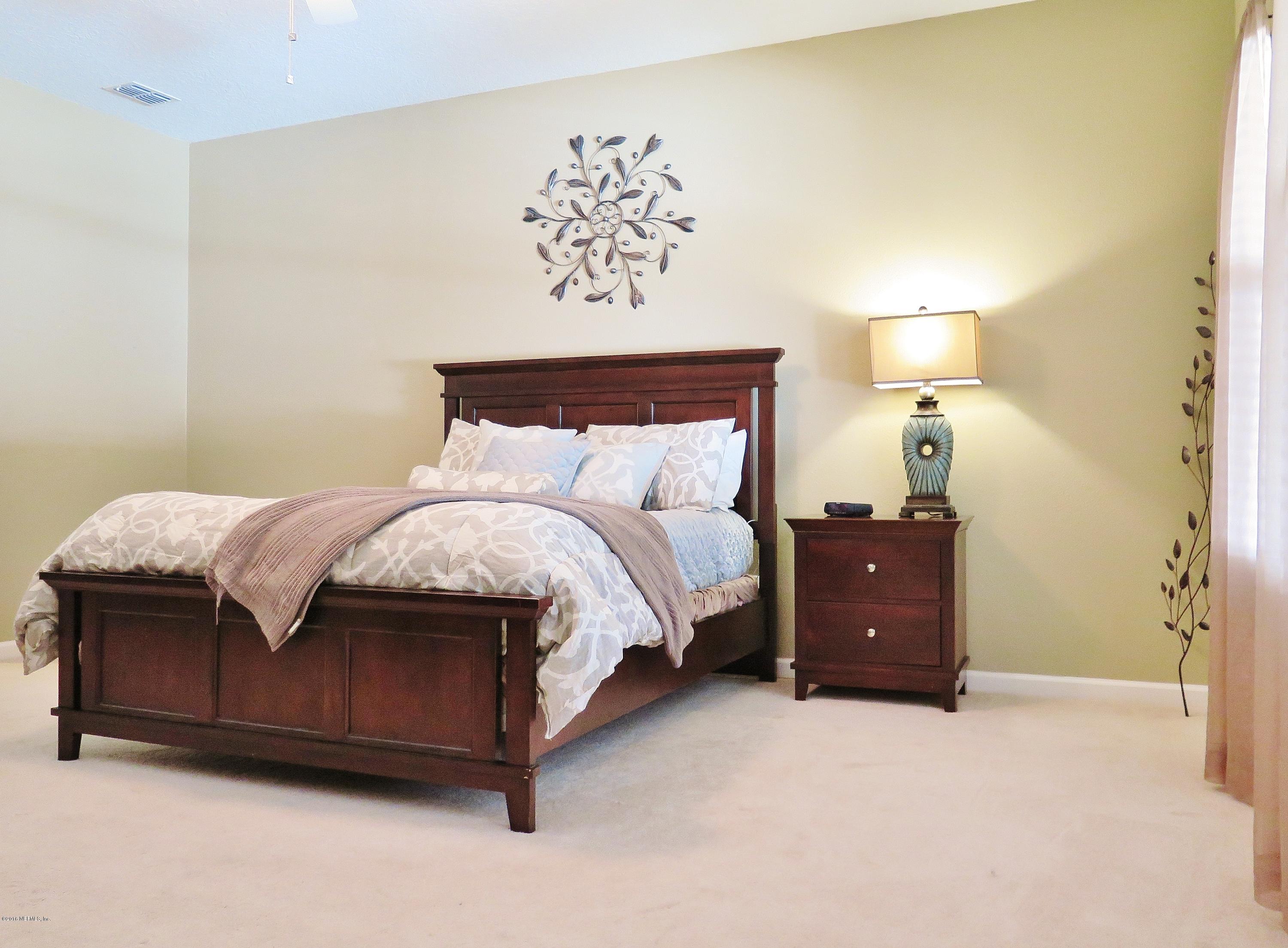 16504 Tisons Bluff Road Jacksonville, FL 32218 - Photo 13 of 34 a spacious bedroom with a bed and a lamp