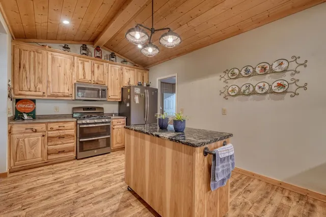 a kitchen with kitchen island stainless steel appliances a stove refrigerator and microwave with wooden floor