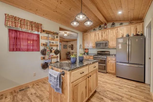 a kitchen with stainless steel appliances granite countertop a refrigerator a stove a sink dishwasher and a refrigerator with wooden floor